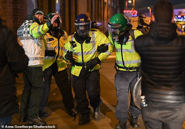 A police officer helps an injured colleague away from the unrest