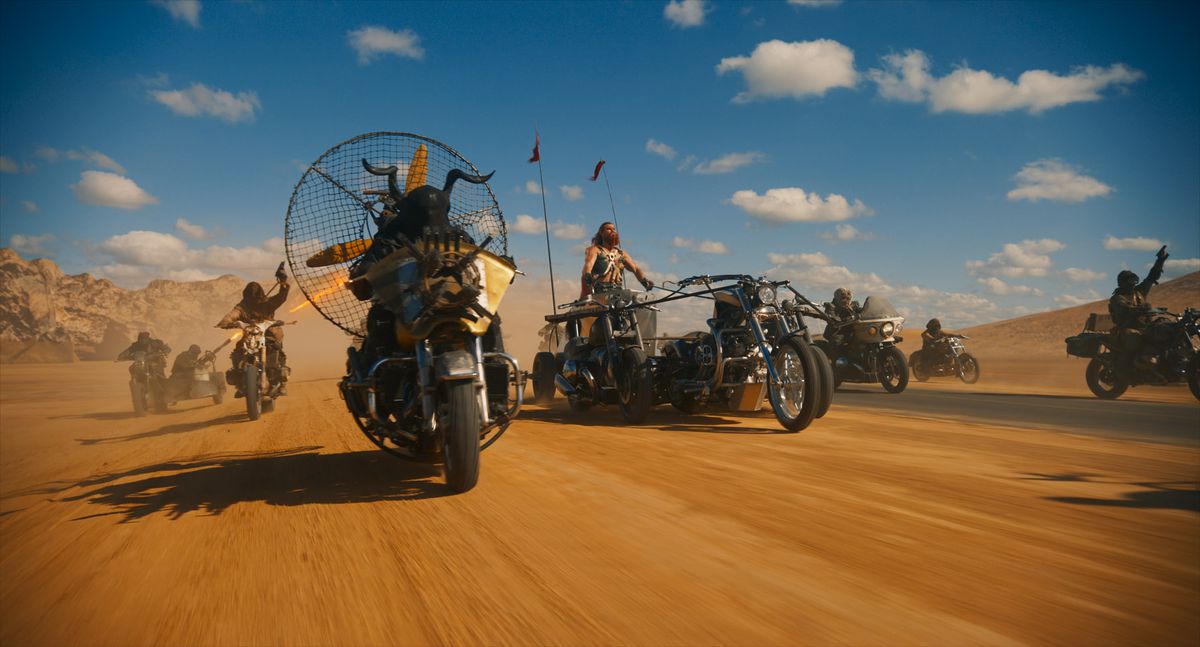 Several characters drive through the desert on makeshift vehicles led by Chris Hemsworth in the spin-off film Furiosa the Mad Max