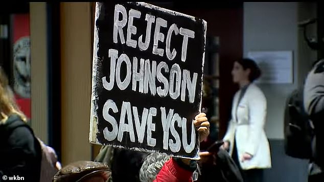 A protester can be seen holding a sign that reads, “Reject Johnson, Save YSU.”