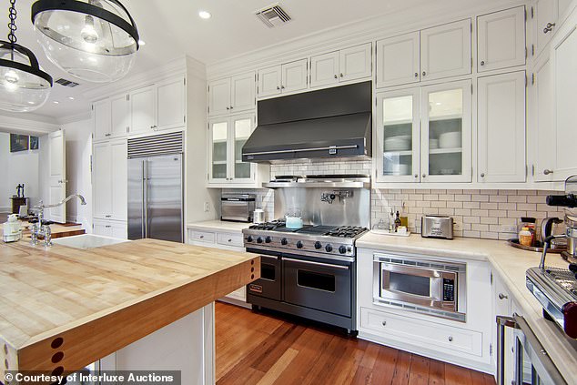 The sleek kitchen features multiple marble countertops, a wine cooler, a sub-zero refrigerator and a pantry