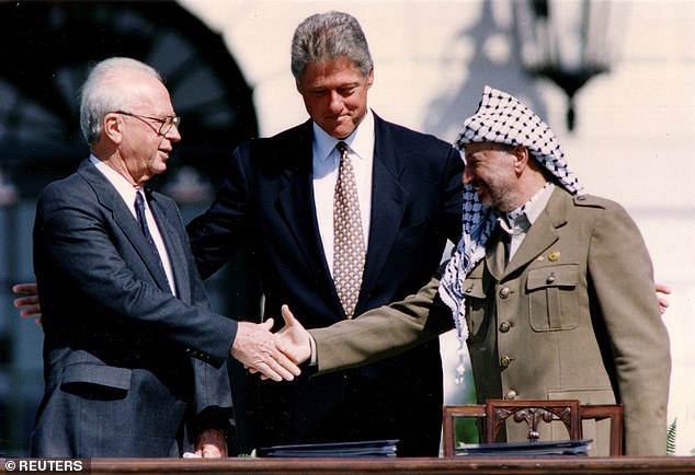 Yasser Arafat (R) shakes hands with Israeli Prime Minister Yitzhak Rabin (L), while US President Bill Clinton stands between them