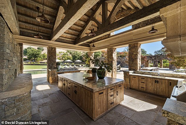 The outdoor kitchen has wooden beams and finishes, stone walls and marble tops