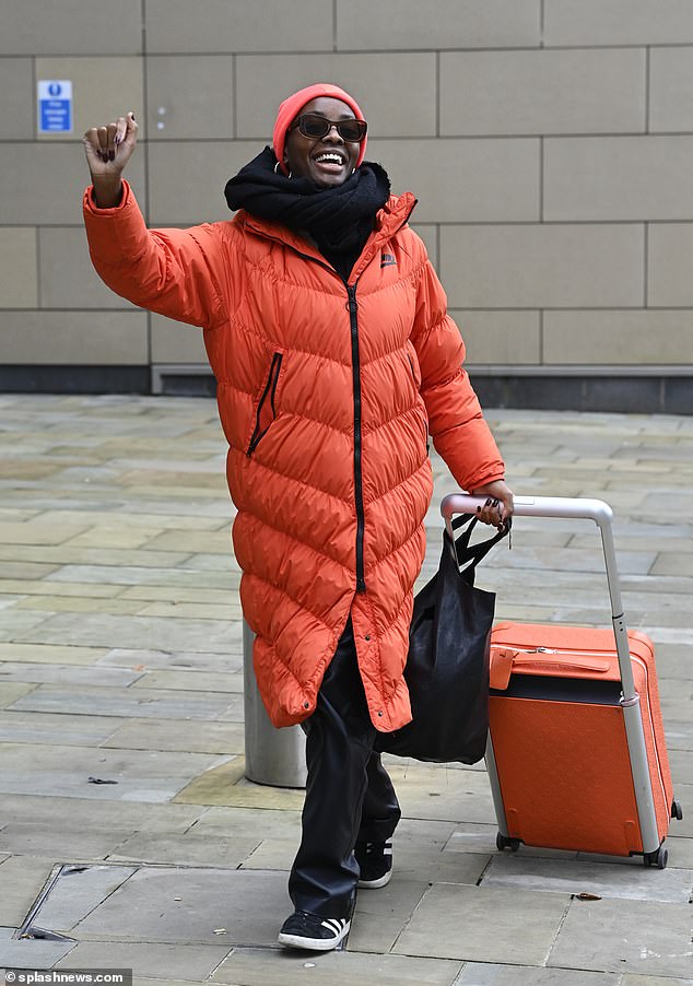 Television presenter AJ, 35, looked cozy in a bright orange padded coat that reached her knees as she pulled a suitcase in the same color behind her in Media City, Salford