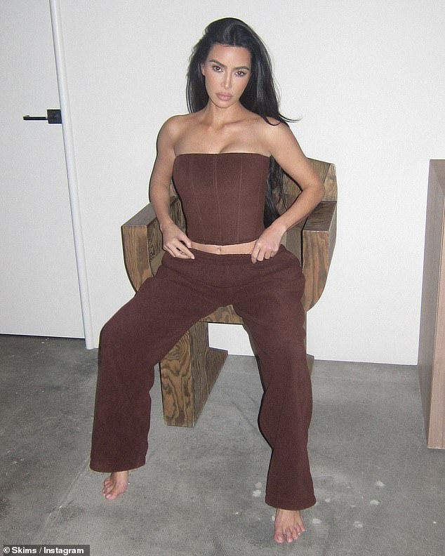 Kim also shared two new SKIMS outfits on the company's Instagram on Sunday, each in their own posts.  She posed in a chocolate brown corset and lounge pants as she sat on a wooden chair
