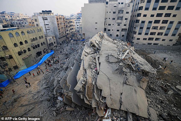 People walk around the ruins of a building destroyed during Israeli attacks in Gaza City on October 8