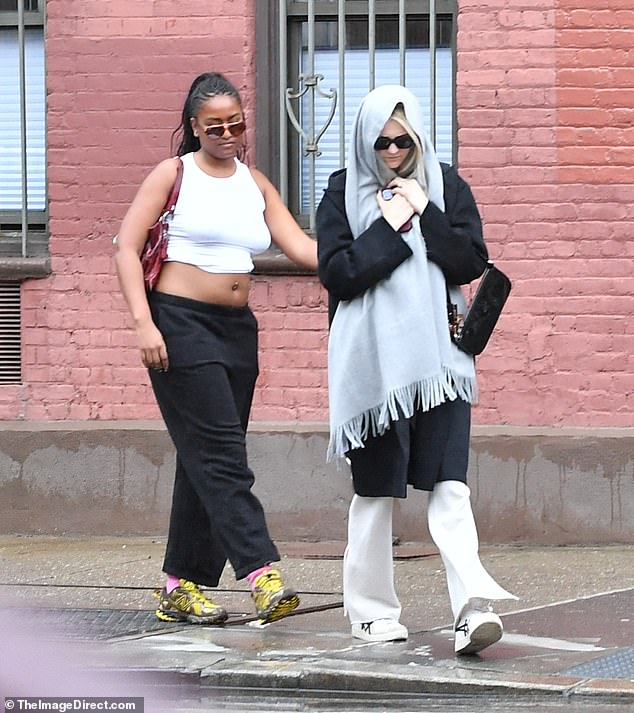 Sasha ignored the humid chill in the air as she stepped out in a white cropped tank top and low-cut black sweatpants, leaving her belly button piercing visible.