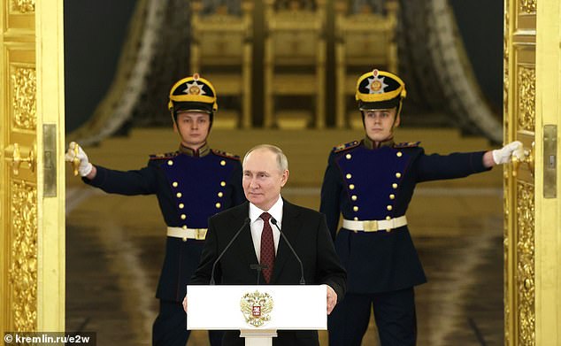 Putin at the event as two guards open the huge golden doors ahead of the Russian president's speech