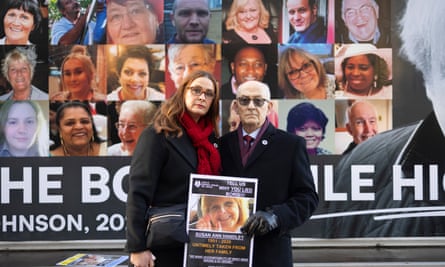 Victoria Morgan and her father, Alan Handley, with a photo of Susan, in front of photos of people who have died from Covid