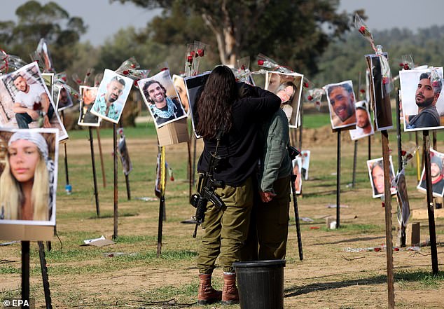 Israeli soldiers comfort each other next to the photos of the victims of the Nova music festival at the festival site near Kibbutz Reim on December 1