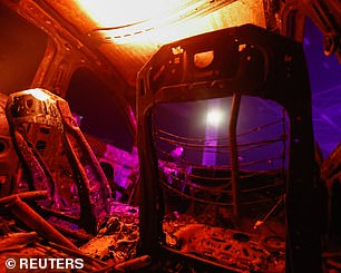 A person looks into a burned out car