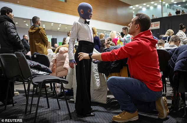 Roman's proud father holds his son by the waist as he looks up at the brave eight-year-old who has found joy in dancing after losing his mother in a Russian missile attack