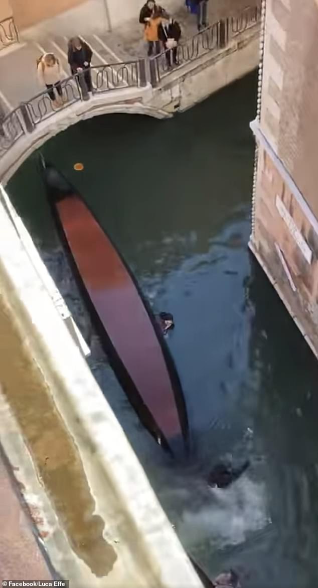 From above a capsized gondola around which tourists still swim in Venice