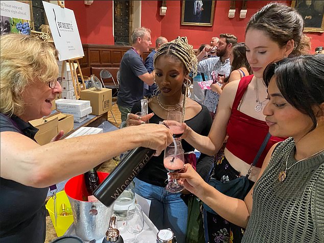 People are seen testing Winewizard at the Oxford Wine Festival, with the tester aerating a glass of red wine