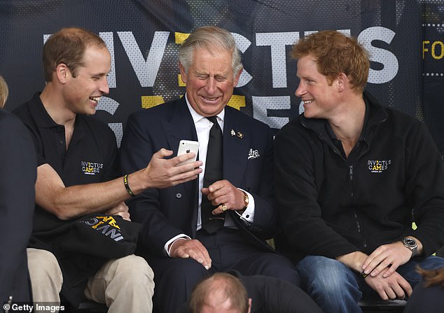 Charles seems fascinated by what Prince William has on his phone to show him at the Invictus Games in 2014