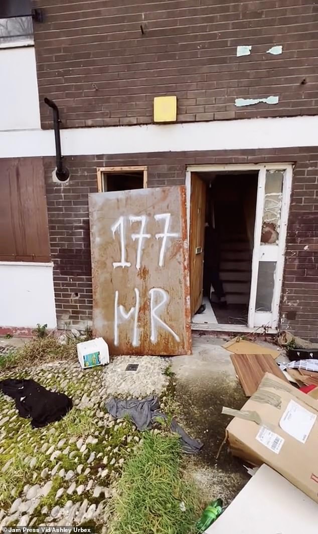 Two flats on the site caught fire in March this year.  Pictured: A door covered in graffiti in a front yard full of trash