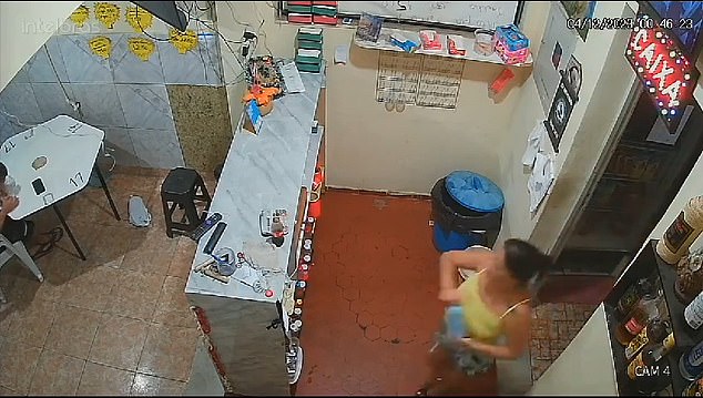 Ana María Paixaõ walks out of the storeroom of her fish market with a bottle containing a flammable liquid that she used to set her husband on fire.  She told police investigators she was defending herself after he hit her, a claim they denied