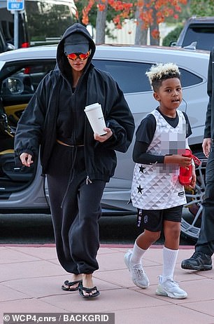 He was carrying a red water bottle and seemed cheerful as he entered the building with his mother