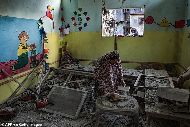 A woman tries to save some books in a daycare center that was hit by an Israeli bomb attack in Rafah on Saturday