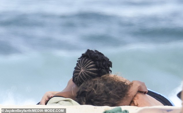 The pair couldn't keep their hands off each other as they tenderly embraced while lying on the beach