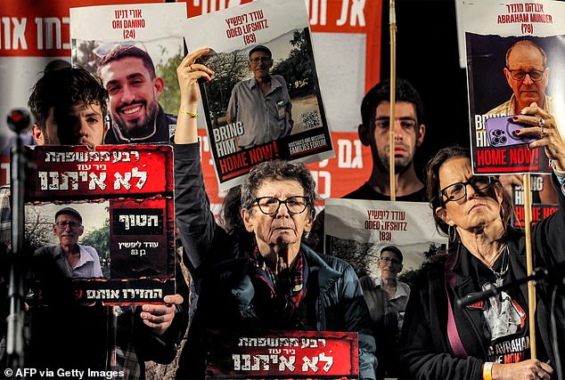 Yocheved Lifshitz (center), who was released by Hamas after 16 days in captivity, holds a photo of her imprisoned husband Oded Lifshitz as she attends a protest with others holding signs with portraits of other Israeli hostages held since the October 7 attacks Gaza are being held