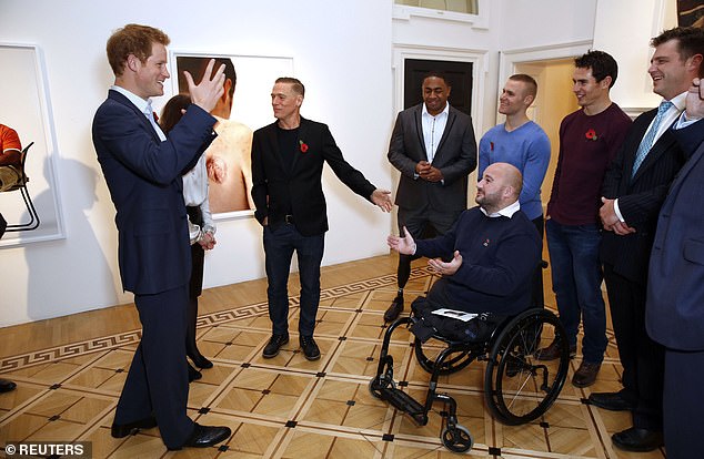 Prince Harry (pictured, left) along with Bryan Adams (left) speak to soldiers during a private viewing of a photo exhibition by Bryan of young wounded soldiers and women from the conflicts in Iraq and Afghanistan