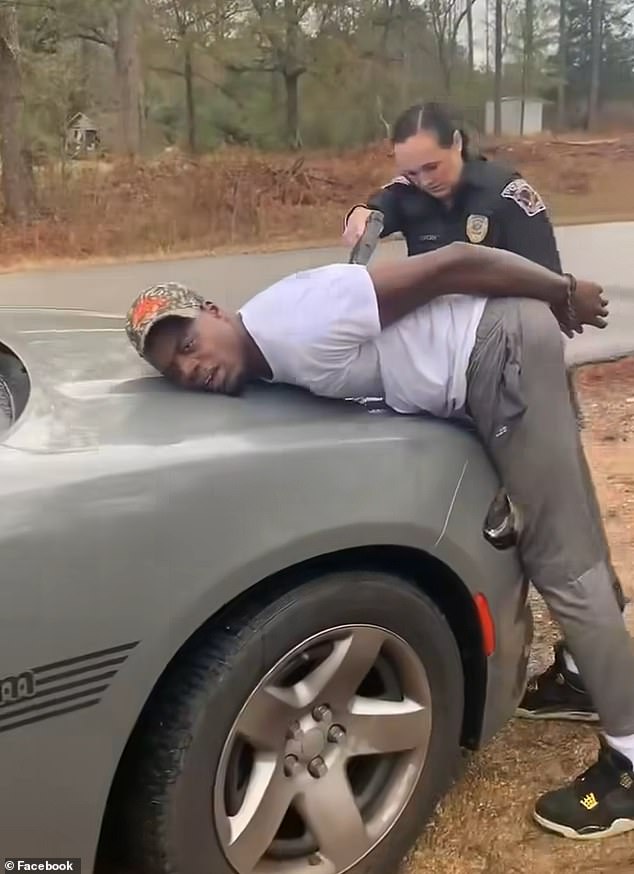 As Washington lies against the front of the car, the police officer tells him to 