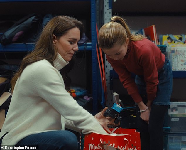 During the visit, Princess Charlotte, aged eight, wearing a red top and denim skirt, is pictured helping her mother pack bags