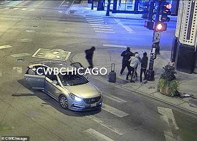 Four masked suspects attacked a woman on a busy Chicago street and robbed her at gunpoint