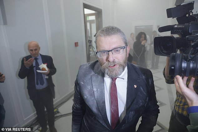 Braun speaks to the media while covered in white powder after extinguishing the Hanukkah candles in the Polish Parliament