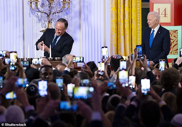 President Joe Biden watches as Second Gentleman Douglas Emhoff lights the menorah during a Hanukkah holiday reception in the East Room of the White House