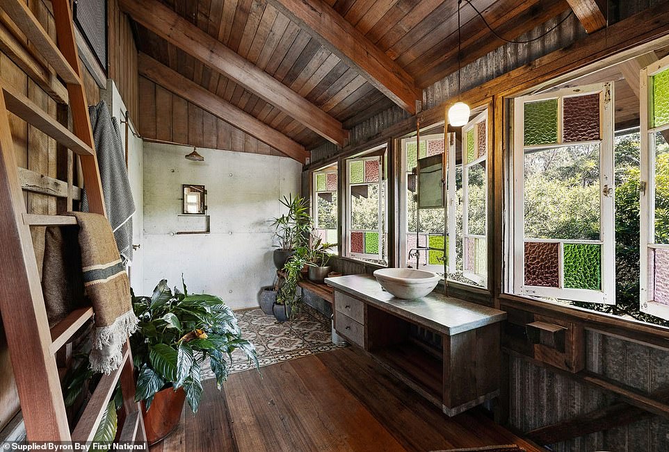 The master bedroom's ensuite is located at the end of a home office and features an open-plan shower with decorative tiles, stained glass windows and brass taps, in keeping with the shabby-chic theme of the house.