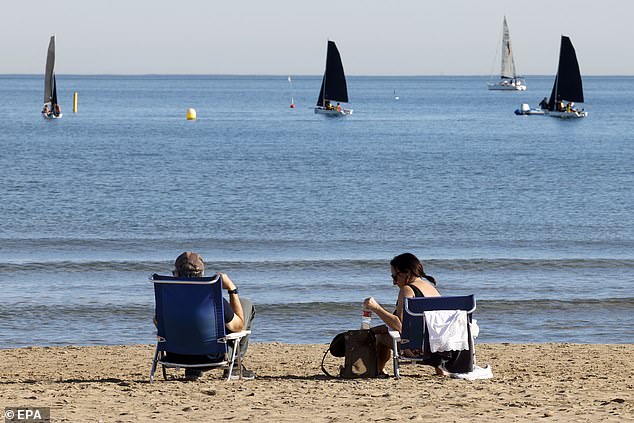 The scorching temperatures enjoyed by these beachgoers on Malaga's Malvarrosa beach come as world leaders agreed for the first time to move away from fossil fuels at the COP28 climate talks.