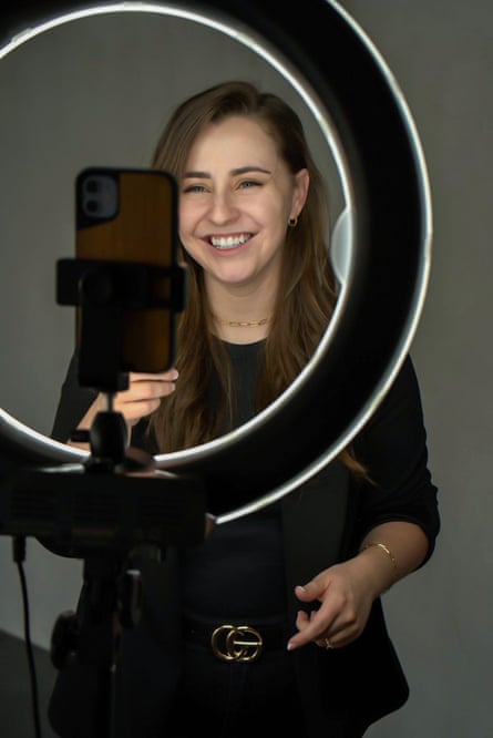 woman smiles in front of ring light because she appears in online videos