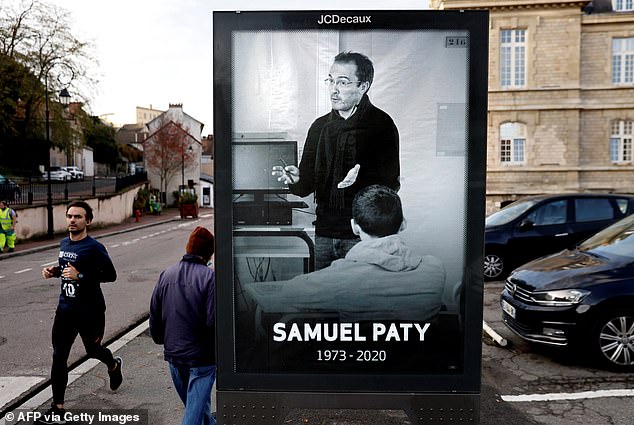 Pedestrians pass a poster depicting French teacher Samuel Paty on November 3, 2020, after the teacher's beheading on October 16