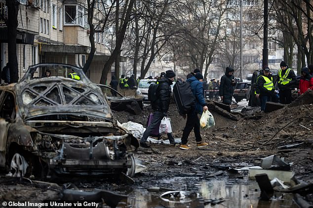 People with bags walk past a damaged apartment building in the Ukrainian capital Kiev after a Russian missile attack on December 13