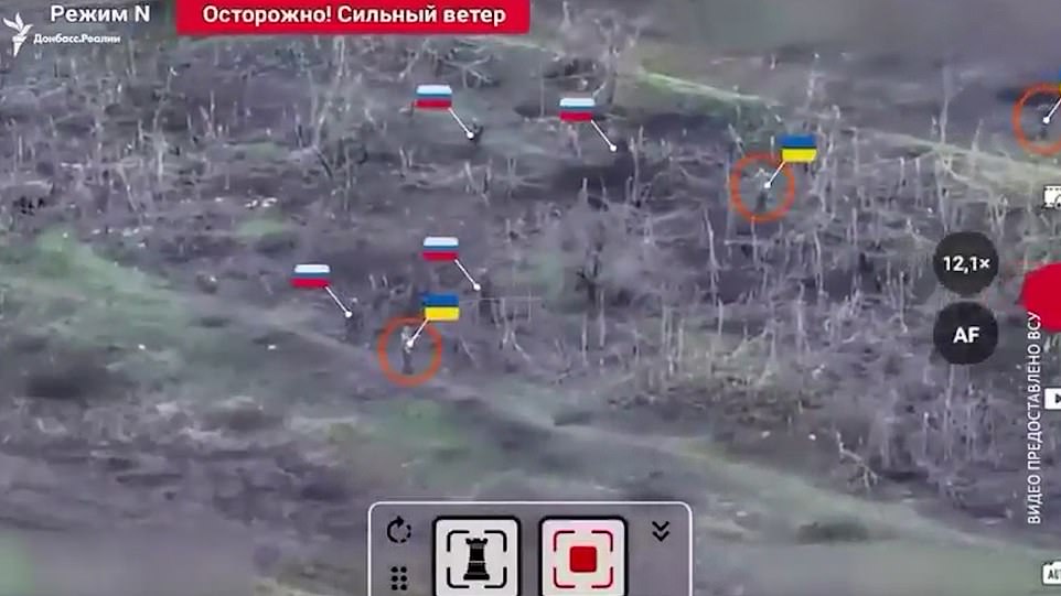 The newly released drone footage (pictured) shows Russian forces advancing towards a grove of dead, leafless trees, presumably aiming to clear a position occupied by Ukrainian forces.  A Russian soldier is seen walking behind a Ukrainian soldier, firing shots at what are believed to be Ukrainian positions among the trees