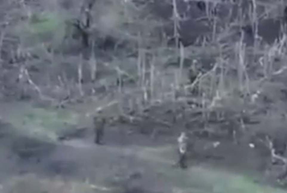 The Ukrainian POW (right) is seen unarmed, while the armed Russian soldier enters the road right behind him