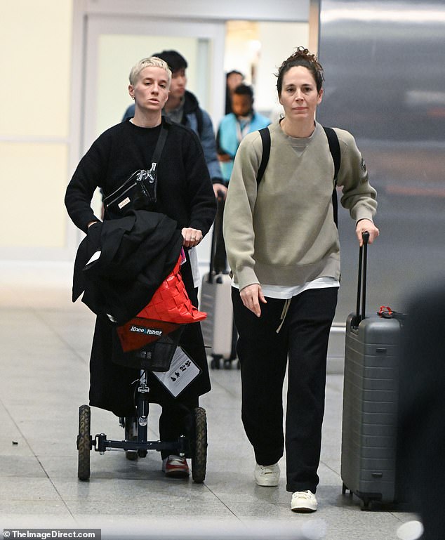 Rapinoe cut a somber figure next to fiancée Sue Bird after flying back into JFK Airport