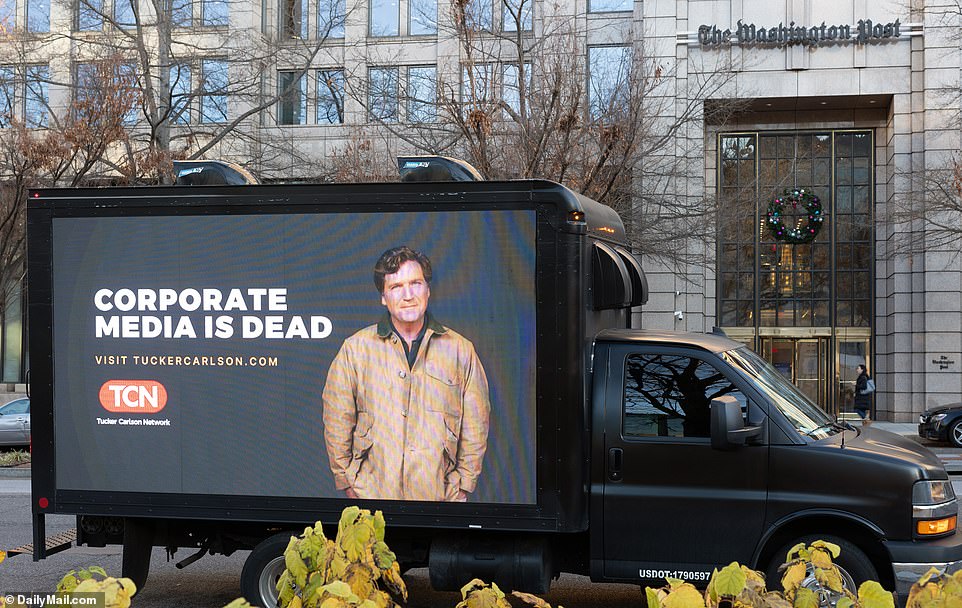 “The era of dominance by a few big media companies, the era of total control of all information by nine people, that's over,” Tucker said.  A billboard was pictured in front of The Washington Post headquarters on Thursday