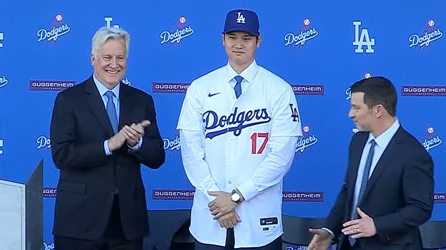 Ohtani poses for photos after donning his No. 17 uniform at a packed press conference