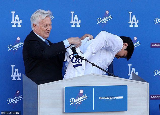 Dodgers owner Mark Walter helps Ohtani put on his blue uniform for the first time