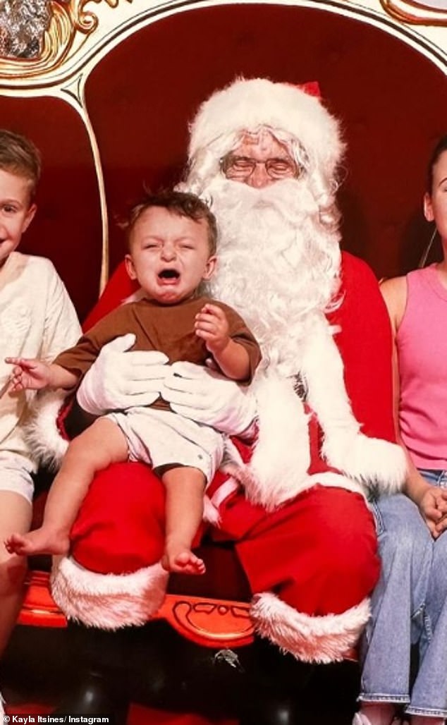 Kayla Itsines, 32, shared a photo of her 11-month-old son Jax crying hysterically on Tuesday as she posed for his Santa photo