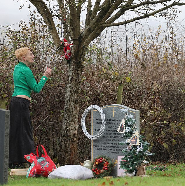 Jackiey worked hard to create a festive scene at the graveside, as she placed an Elf On A Shelf mascot on a nearby tree, erected Christmas tree-shaped decorations and then vigorously polished the headstone with a cloth.