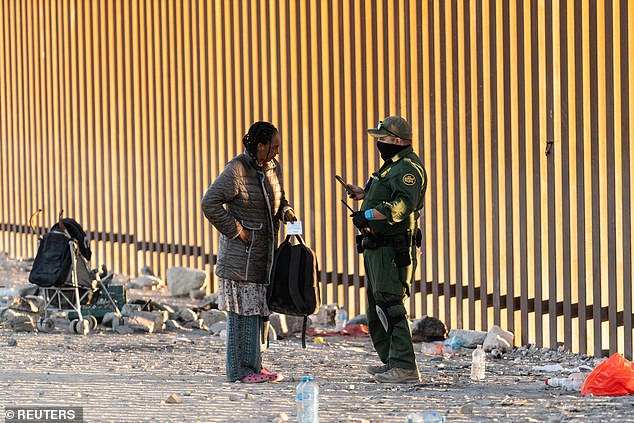 A migrant speaks with the US Border Patrol agent after crossing the border wall into the US from Mexico as the number of migrants rises in the border town of Lukeville, Arizona, US December 14, 2023