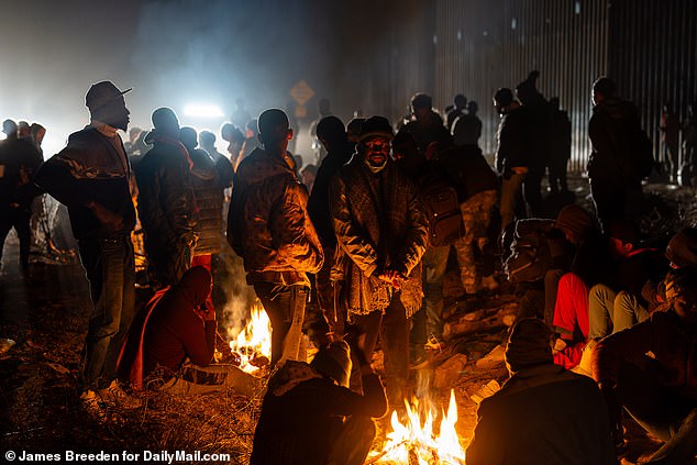 Migrants warm up by the fire in Lukeville, Arizona.  In the Tucson region, which includes Lukeville, a record 12,000 migrants crossed in one day last week
