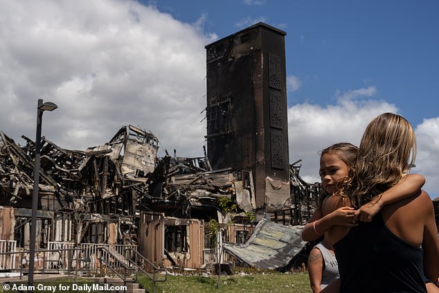 People stand outside a burned down affordable housing complex in Lahaina.  The Maui County Council is also considering legislation for property tax breaks for owners who convert