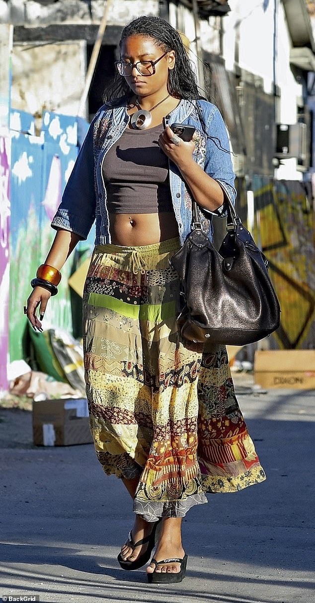 She wore a brown cropped T-shirt – which left her pierced navel on full display – and a long, flowing maxi skirt with different patterned stripes on it.