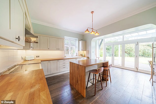 The kitchen has ivory-colored lower and upper cabinets and large French doors leading outside