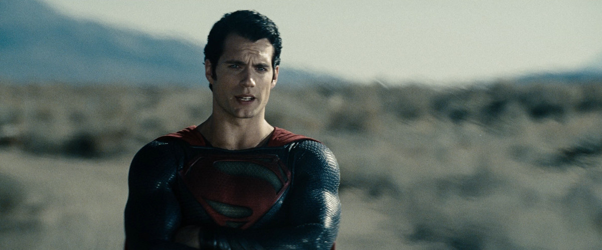 Henry Cavill crosses his arms as he talks with furrowed brows in Man of Steel.