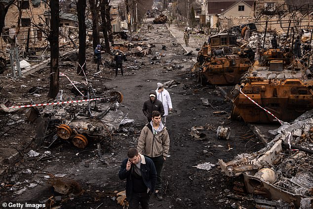 People walk through rubble and destroyed Russian military vehicles on the street on April 6, 2022 in Bucha, Ukraine